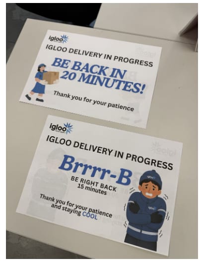 Two printed Igloo delivery-in-progress sign designs on a desk